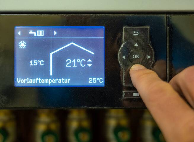 Dieses Bild zeigt die Einstellung der Vorlauftemperatur einer Wärmepumpe. Im Mittelpunkt steht ein digitales Bedienfeld, auf dem eine Person die gewünschte Vorlauftemperatur eingibt. Die Anzeige zeigt aktuell 25°C an, was typisch für eine Fußbodenheizung ist. Die Handhabung des Bedienfelds ist intuitiv, mit klaren und verständlichen Symbolen und einer benutzerfreundlichen Oberfläche. Durch die Anpassung der Vorlauftemperatur kann die Effizienz der Wärmepumpe optimiert werden, was zu einem geringeren Energieverbrauch und niedrigeren Heizkosten führt. Das Bild verdeutlicht die einfache Bedienung moderner Wärmepumpensysteme und ihre Anpassungsfähigkeit an individuelle Bedürfnisse und verschiedene Heizsysteme.