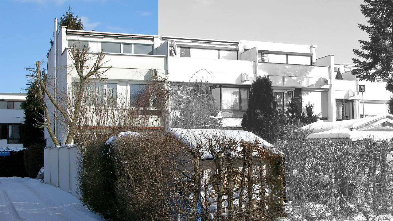 Blick auf ein Einfamilienhaus in München aus den 1970er Jahren mit moderner Architektut , weißen Wänden und schwarzen Giebeln