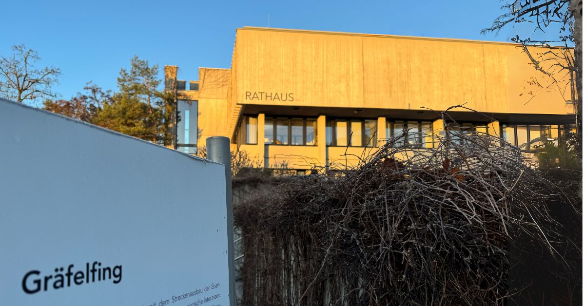 Das Rathaus Gräfelfing im warmen Abendlicht mit einem Schild im Vordergrund, das Gräfelfing als Ausflugsziel beschreibt.