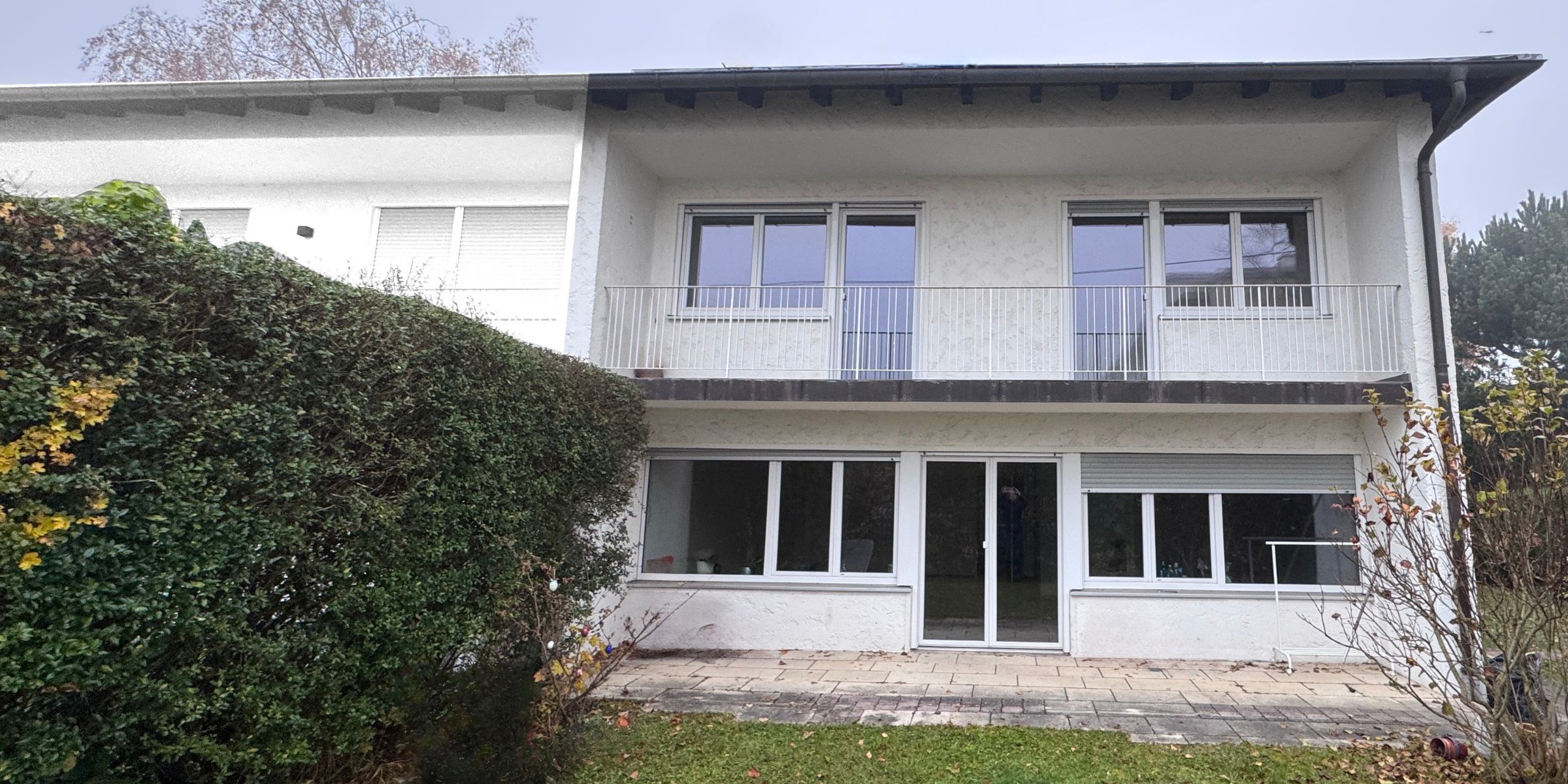 Blick auf ein Einfamilienhaus in München aus den 1970er Jahren mit moderner Architektut , weißen Wänden und schwarzen Giebeln